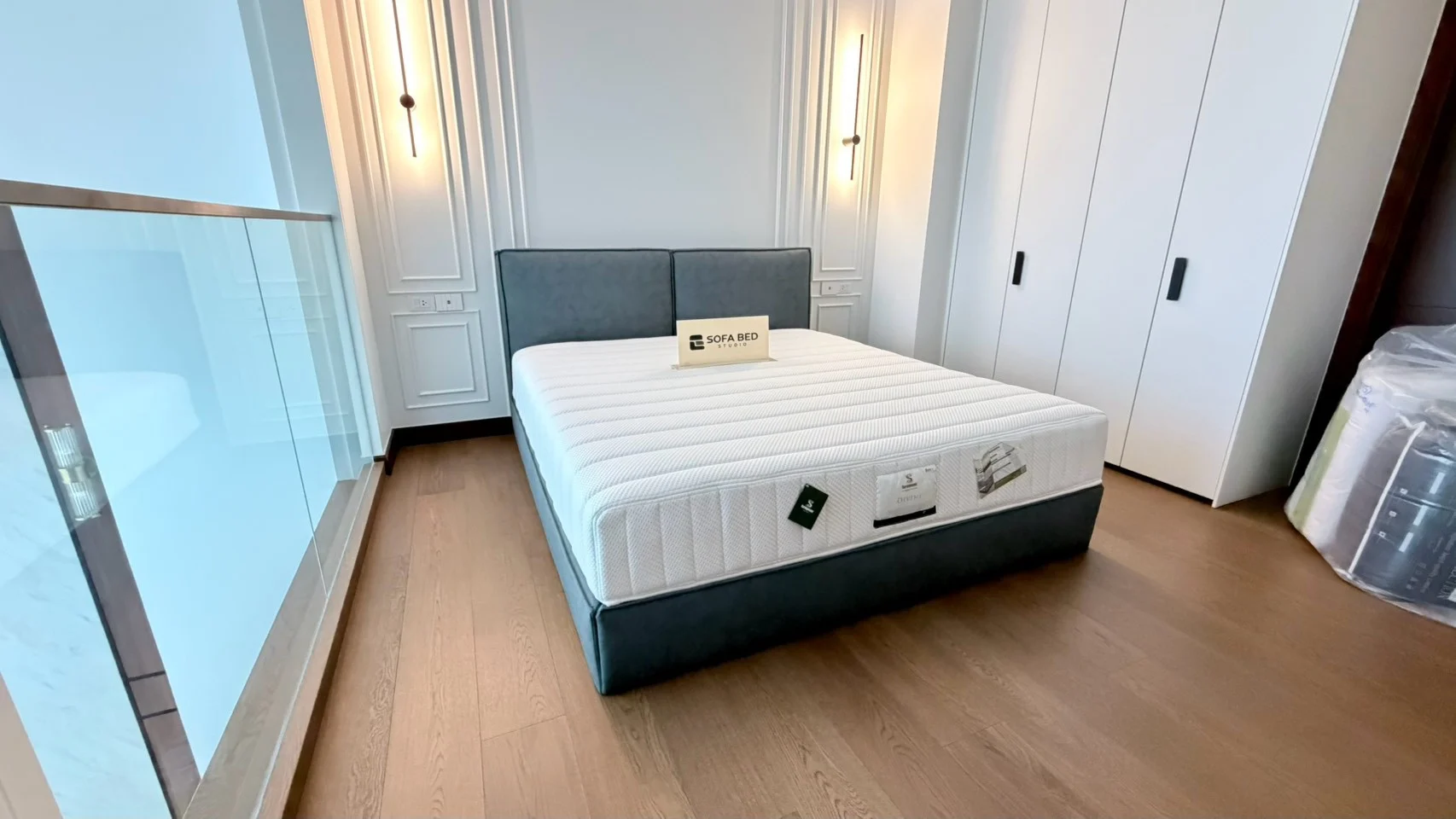 Dark double-square headboard and mattress against a panelled wall