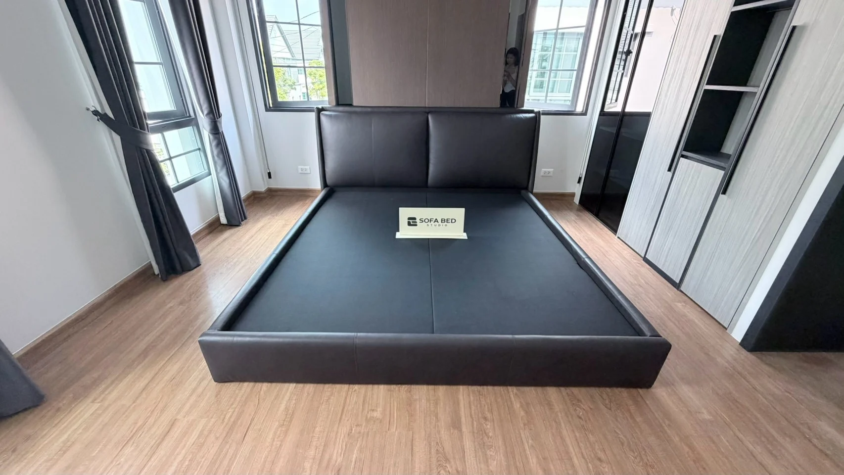 เตียงหัวหมอนสีเข้มในห้องนอนรับแสง · Sofa Bed Studio · PH-027