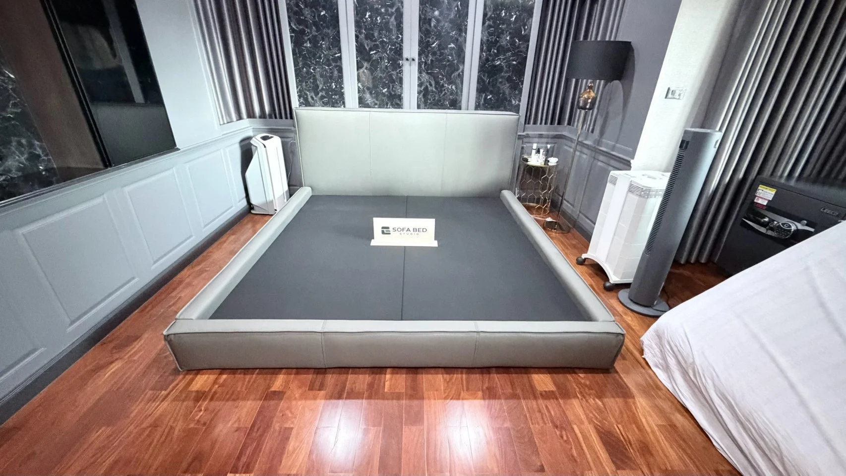 เตียงหัวพาแนลสีเทาในห้องพื้นไม้ · Sofa Bed Studio · SP-075