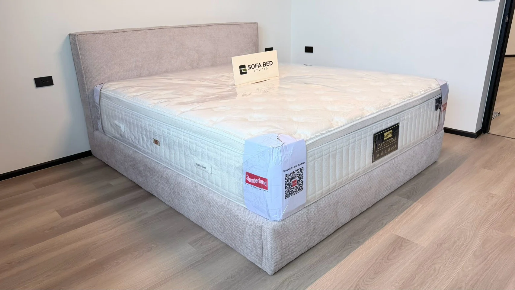 เตียงบุหุ้มสีเบจพร้อมฟูกในห้องพื้นไม้ · Sofa Bed Studio · SP-080