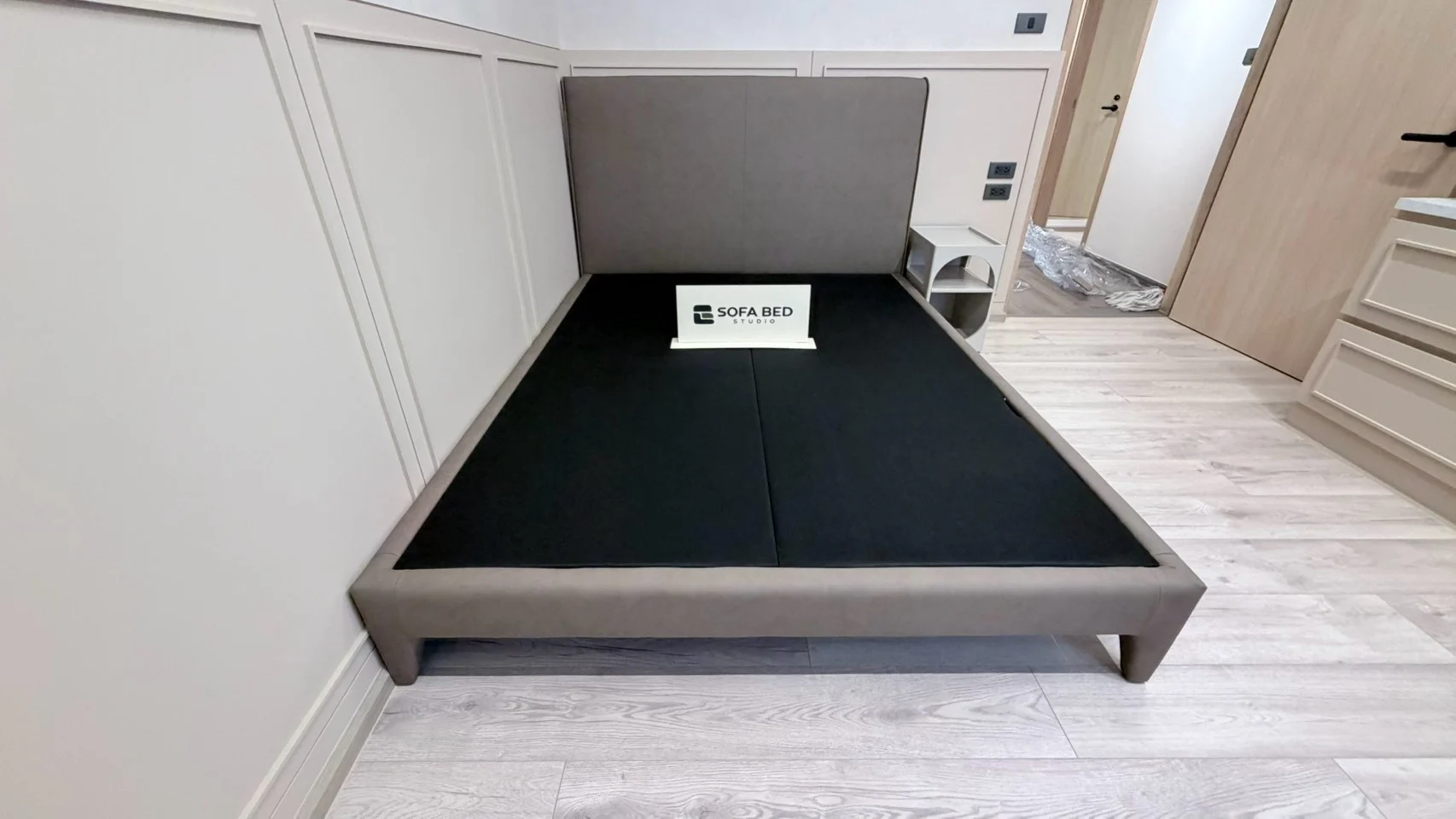 ฐานเตียงสีเทาทรงเรียบในห้องนอนผนังขาว · Sofa Bed Studio · SP-077