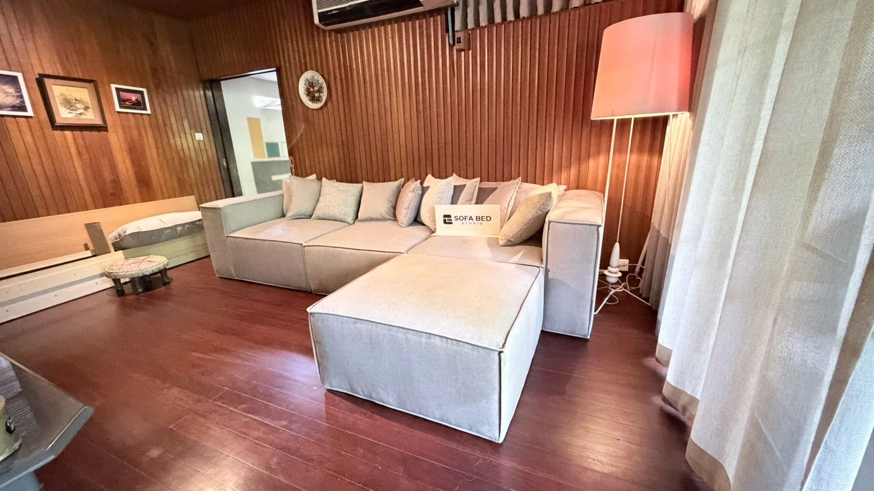 โซฟาโมดูลาร์สีอ่อนพร้อมส่วนพักขาในห้องผนังไม้ · Sofa Bed Studio · SM-073