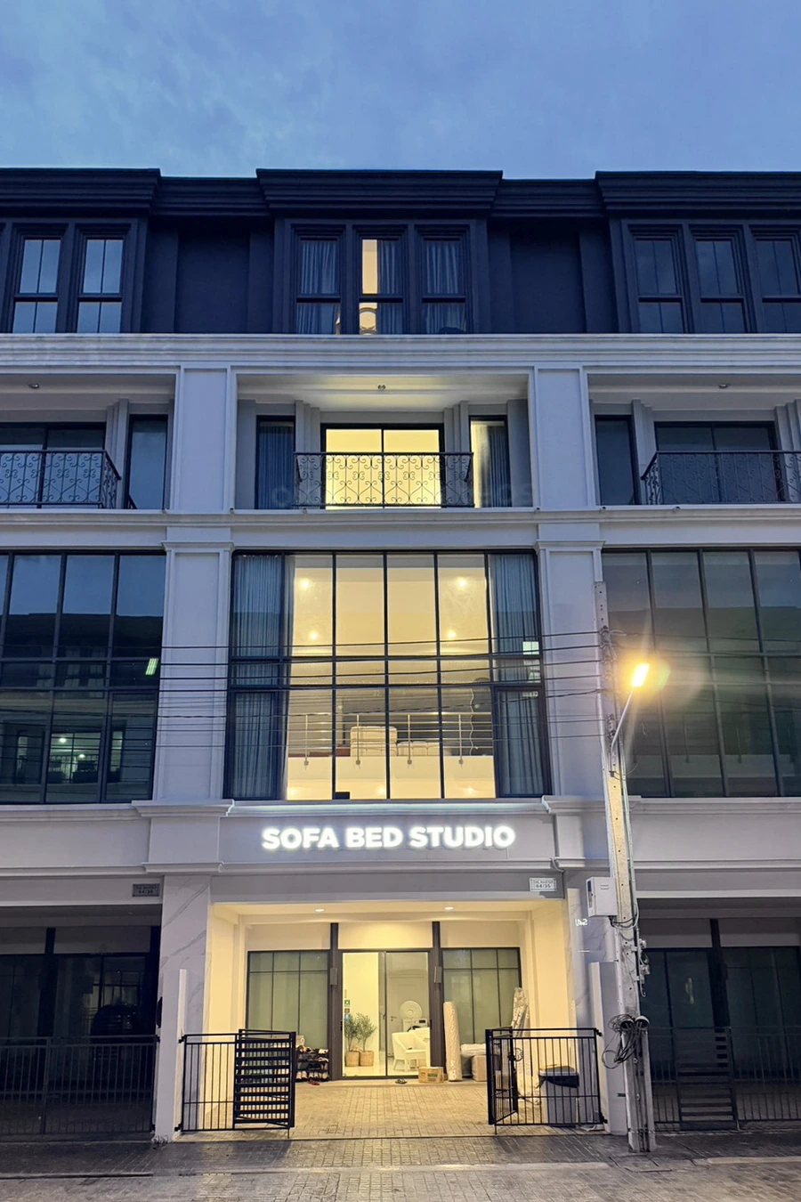 หน้าร้าน Sofa Bed Studio ในช่วงเย็น เห็นป้ายร้านและแสงภายใน